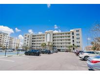 Exterior view of building featuring many floors of condos with a full parking lot and tennis court at 17500 Gulf Blvd # 407, Redington Shores, FL 33708