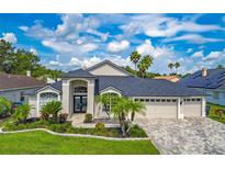 Beautiful single Gathering home featuring lush landscaping, paver driveway, and a three car garage at 18504 Country Crest Pl, Tampa, FL 33647
