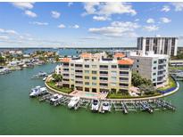 A stunning aerial view of a waterfront condo with boat slips, pool, and bay views on a sunny day at 200 Skiff Pt # 202, Clearwater Beach, FL 33767