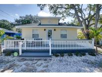 Charming yellow home featuring a cozy front porch with white picket fence and gray deck at 284 North St, Palm Harbor, FL 34683
