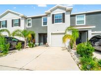 Two-story townhome featuring a one-car garage, manicured landscaping, and a concrete driveway at 2925 Evergreen Elm Pass, Wesley Chapel, FL 33543