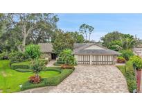 Charming exterior of a home featuring lush landscaping and a paver driveway at 3207 Hilltop Ln, Largo, FL 33770