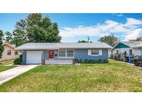 Charming single-story home featuring a well-manicured lawn, red front door, and attached garage at 3271 36Th N St, St Petersburg, FL 33713