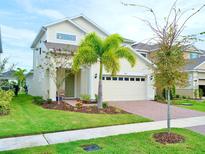 Charming two-story home featuring a well-maintained lawn, a brick driveway, and a welcoming entrance at 6118 Voyagers Pl, Apollo Beach, FL 33572