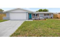 Charming single-story home with a well-maintained lawn and a striking turquoise front door at 6804 Tierra Verde St, Port Richey, FL 34668