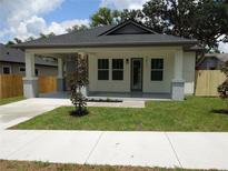 Charming single-story home with a welcoming front porch, landscaped lawn, and modern design elements at 7011 N 15Th St, Tampa, FL 33610