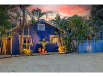 Charming blue home with tropical landscaping and a white picket fence at 722 Gulf Blvd, Indian Rocks Beach, FL 33785