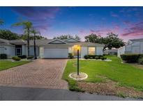 Charming single-story home featuring a brick driveway, well-manicured lawn, and tasteful landscaping at 746 Masterpiece Dr, Sun City Center, FL 33573
