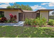 Inviting home exterior with lush lawn, colorful landscaping, and a charming gated courtyard entrance at 8436 60Th N St # 304, Pinellas Park, FL 33781