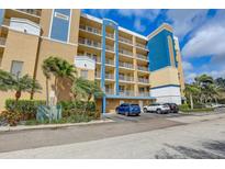 Low-angle view of a multi-story tan and blue condo building with parking at 960 Starkey Rd # 2405, Largo, FL 33771