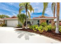 Charming single-story home with a Spanish tile roof, stone accents, lush landscaping, and a well-maintained driveway at 9909 San Mateo Way, Port Richey, FL 34668