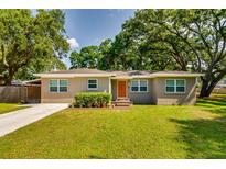Charming single-story home featuring a well-manicured lawn, mature trees, and inviting curb appeal at 1403 W Pradera Ave, Tampa, FL 33612