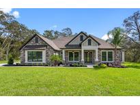 Beautiful stone-accented home with lush lawn and meticulous landscaping under a blue sky at 17404 Nokota Ave, Hudson, FL 34667