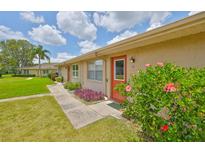 Charming condo with a well-manicured lawn, beautiful landscaping, and a red door, creating a welcoming entrance at 1904 Canterbury Ln # 18, Sun City Center, FL 33573
