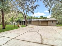 Charming ranch-style home with mature trees and a spacious driveway leading to an attached garage at 27315 Popiel Rd, Brooksville, FL 34602