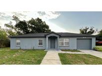 Charming single-story home with gray exterior, well-maintained lawn, and an attached garage at 404 Water St, Plant City, FL 33563