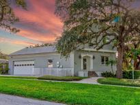 Charming two-story home with a brick exterior, lush green lawn, and mature trees creating a picturesque setting at 504 Riverside Dr # 504, Tarpon Springs, FL 34689