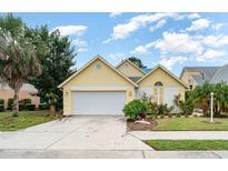 Charming yellow home featuring a two-car garage, well-maintained landscaping and a welcoming front entrance at 7833 Ontario Street Cir, Sarasota, FL 34243