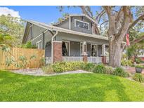 Charming gray two-story home with a welcoming front porch, beautiful landscaping, and mature trees at 1005 Main St, Safety Harbor, FL 34695