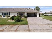Well-maintained single-story home with a carport and manicured front lawn and mature landscaping at 1633 Bentwood Dr, Sun City Center, FL 33573