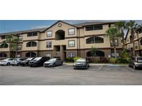 Three-story building featuring tan stucco, brown trim, screened-in balconies, palm trees, and parking at 16431 Enclave Village Dr # 16431, Tampa, FL 33647