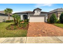 Charming single-story home featuring a well-manicured lawn, brick driveway, and neutral exterior paint at 19664 Ship Wheel Way, Land O Lakes, FL 34638