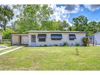 Charming single-story home featuring awnings, a carport, green grass, and beautiful landscaping at 6004 S 82Nd St, Tampa, FL 33619