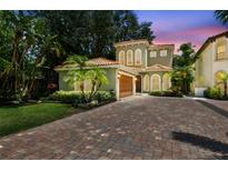 Charming two-story home boasts lush landscaping, a terracotta tile roof, and a brick driveway at 6008 Interbay Blvd, Tampa, FL 33611
