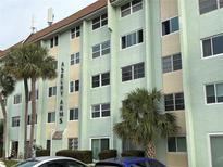 Multi-story light green condo building featuring palm trees and manicured landscaping at 801 83Rd N Ave # 107, St Petersburg, FL 33702