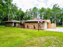 Lovely home with stone accents, lush landscaping, American flags, and a well-maintained lawn at 1025 Reading Rd, Lutz, FL 33558