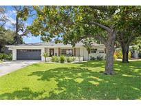 Charming single-story home with well-manicured lawn, mature trees, and an attached two-car garage at 125 Live Oak Ln, Largo, FL 33770
