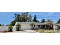 Charming one-story home featuring a well-manicured lawn, attached garage, and inviting front entrance at 14530 Apache Ave, Largo, FL 33774