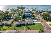 Stunning aerial view of coastal homes with manicured lawns and views of the bay in the distance at 1794 Santa Barbara Dr, Dunedin, FL 34698