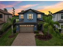 Beautiful two-story home with a brick driveway, blue exterior, lush landscaping, and a two-car garage at 19191 Pease Pl, Lutz, FL 33558