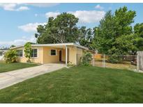 Quaint one-story home with a lush green lawn, driveway, and mature landscaping at 2044 Temple Ter, Clearwater, FL 33764