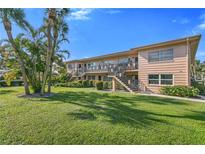 Two-story condo building with lush green lawn, mature palms, and private entrances via exterior staircases at 216 36Th N Ave # 202B, St Petersburg, FL 33704