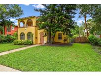 Charming yellow two-story home with a lush green lawn and mature trees in a desirable neighborhood at 2227 Brevard Ne Rd, St Petersburg, FL 33704