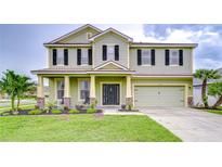 Two-story home with a two-car garage, front porch with stone accents, and manicured lawn at 3012 Magnolia Meadows Dr, Plant City, FL 33567