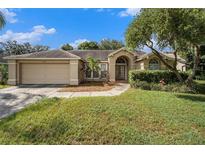 Charming single-story home featuring a manicured lawn, mature landscaping, and a two-car garage at 4303 Kipling Ave, Plant City, FL 33566