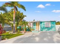 Charming turquoise bungalow featuring lush tropical landscaping and a bright yellow door at 4570 67Th N St, St Petersburg, FL 33709