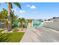 Charming turquoise home featuring a manicured lawn, palm trees, and a long driveway, perfect for island living at 4570 67Th N St, St Petersburg, FL 33709