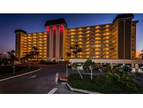 Well-lit condominium building with palm trees and a circular driveway at dusk at 4750 Cove Cir # 1001, St Petersburg, FL 33708