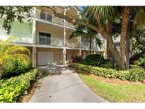 Three-story home featuring multiple balconies, a ground-level garage, and lush tropical landscaping at 512 1St St # 108, Indian Rocks Beach, FL 33785
