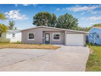 Charming gray single-story home with a well-manicured lawn and a driveway leading to an attached garage at 5326 22Nd N Ave, St Petersburg, FL 33710
