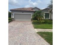 Charming home featuring a tile roof, paver driveway and lush landscaping at 12619 Richezza Dr, Venice, FL 34293