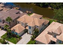 An aerial view of a two-story home boasting a tile roof, paved driveway and access to the water at 18050 Cozumel Isle Dr, Tampa, FL 33647
