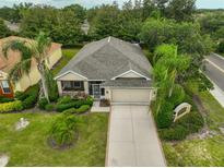 Charming single-story home features lush landscaping, screened porch, two-car garage, and a well-maintained lawn at 2128 Worthington Greens Dr, Sun City Center, FL 33573