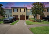Inviting townhome featuring colorful exterior, a single-car garage, well-kept lawn, and a paved driveway at 2435 Edgewater Falls Dr, Brandon, FL 33511