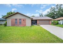Charming single-story home with brick accents, well-maintained lawn, and two-car garage at 2608 Camille Dr, Palm Harbor, FL 34684