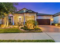 Charming home featuring manicured landscaping and a brick driveway leading to an attached two-car garage at 31921 Magna Gulf Loop, San Antonio, FL 33576